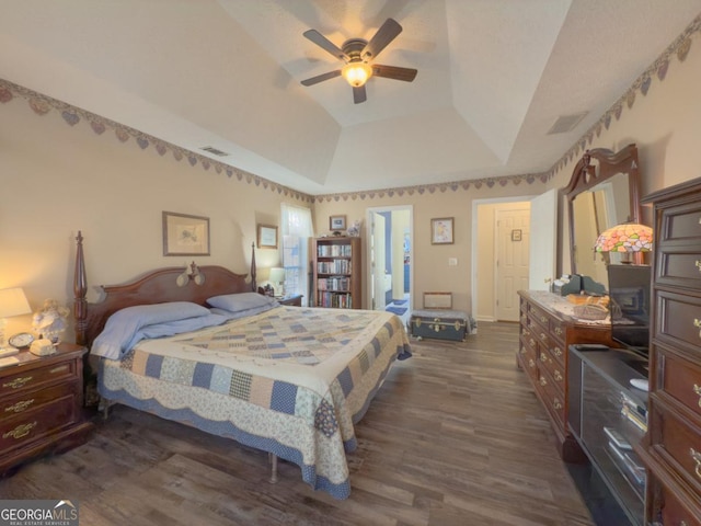 bedroom featuring dark hardwood / wood-style floors, ceiling fan, and a raised ceiling