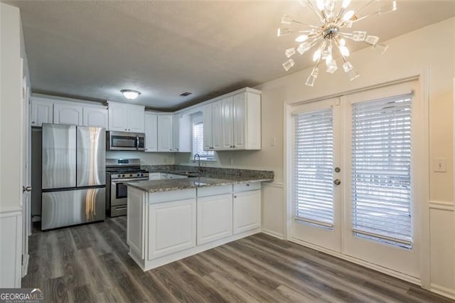 kitchen with dark hardwood / wood-style floors, white cabinetry, stainless steel appliances, light stone countertops, and french doors