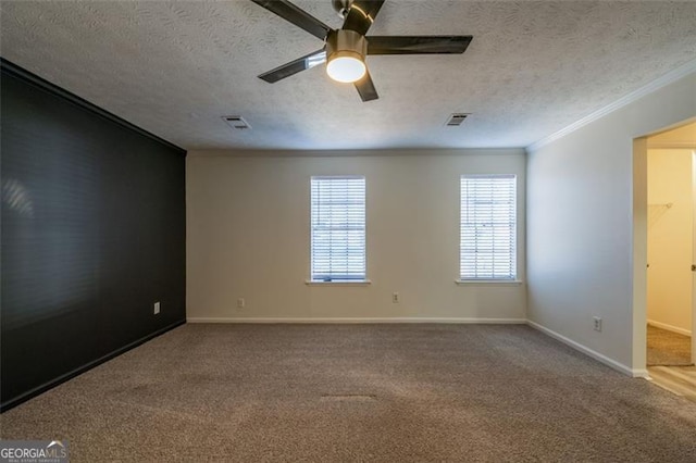 empty room with ornamental molding, carpet floors, ceiling fan, and a textured ceiling