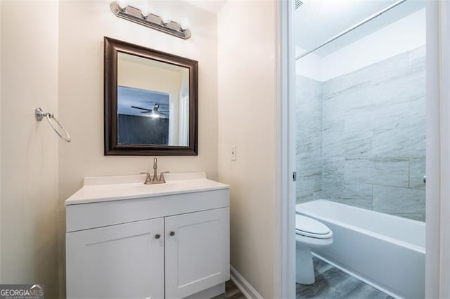 full bathroom featuring hardwood / wood-style flooring, vanity, tiled shower / bath, and toilet