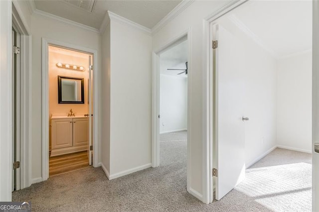 hallway with ornamental molding, sink, and light carpet