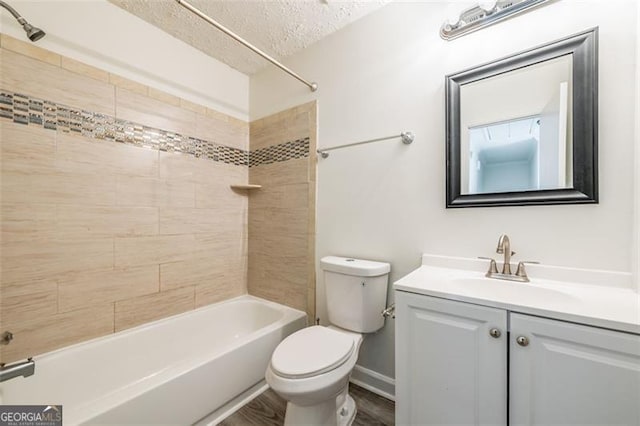 full bathroom featuring toilet, wood-type flooring, a textured ceiling, vanity, and tiled shower / bath combo