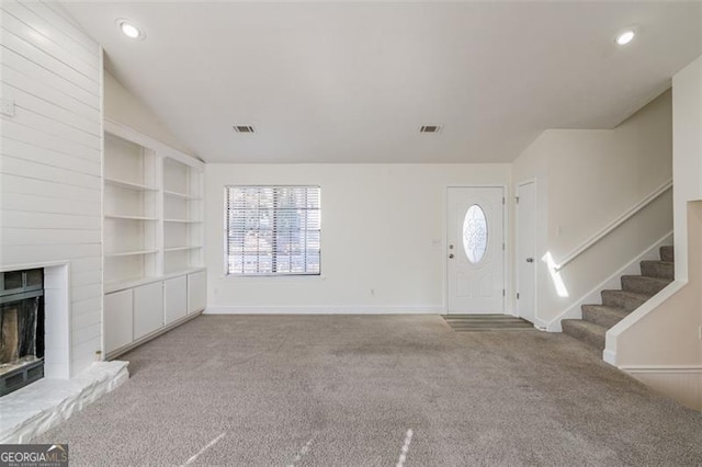 entryway featuring light colored carpet, a fireplace, and vaulted ceiling