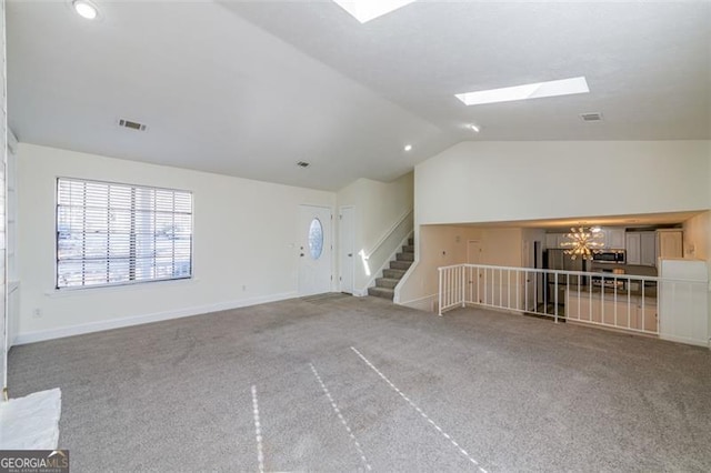 unfurnished living room with carpet floors, vaulted ceiling with skylight, and a chandelier