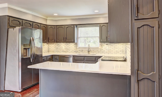 kitchen featuring sink, light wood-type flooring, kitchen peninsula, stainless steel appliances, and decorative backsplash