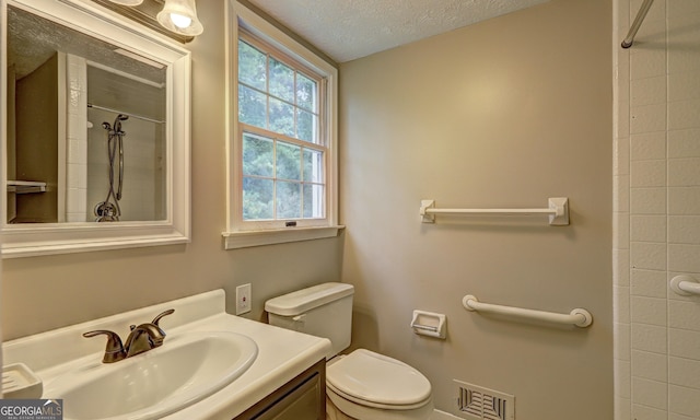 bathroom with walk in shower, vanity, toilet, and a textured ceiling