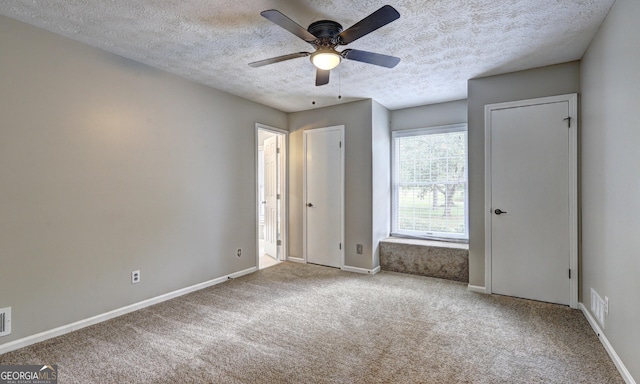 unfurnished bedroom featuring light carpet, a textured ceiling, and ceiling fan