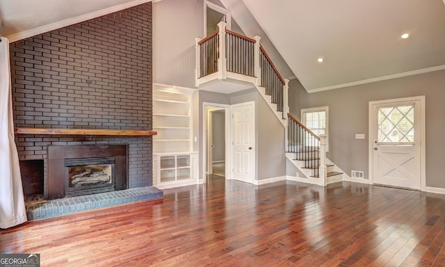 unfurnished living room featuring high vaulted ceiling, ornamental molding, hardwood / wood-style floors, and a brick fireplace