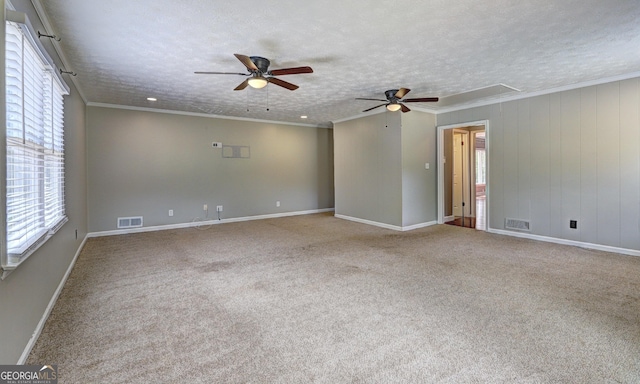 empty room with a wealth of natural light, crown molding, light colored carpet, and a textured ceiling