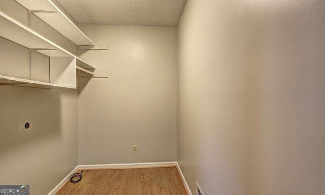 laundry room featuring wood-type flooring, hookup for an electric dryer, and a textured ceiling