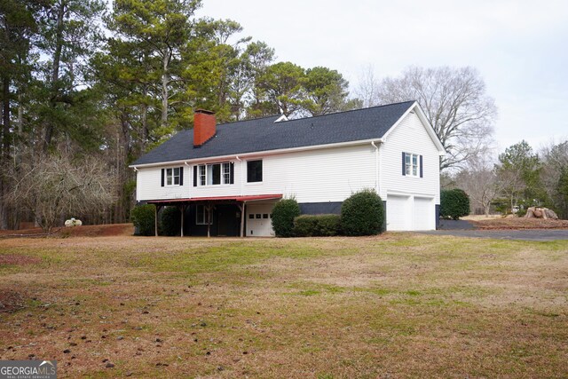 rear view of property with a yard and a garage