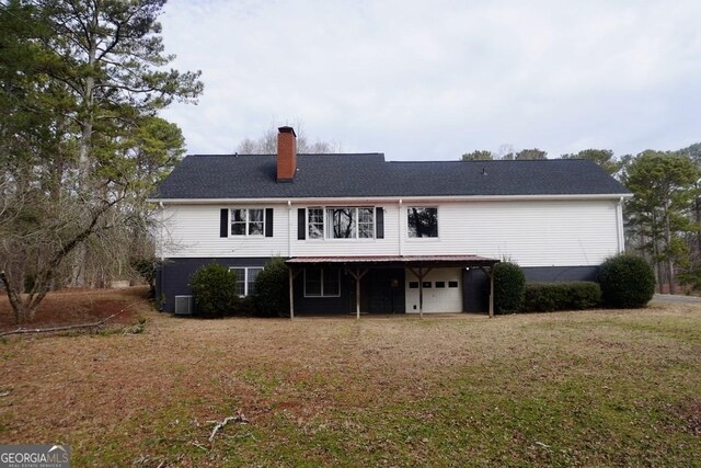 rear view of property with central AC, a garage, and a yard