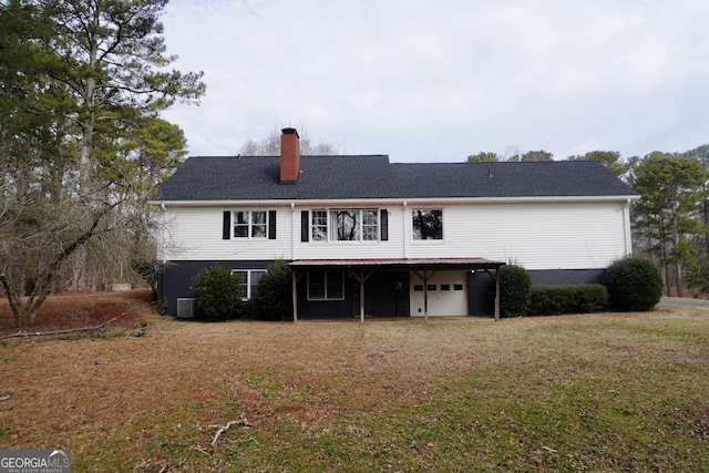 rear view of property featuring a yard, a garage, and central AC