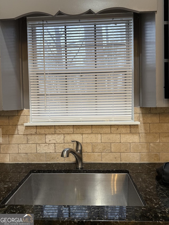 interior details with sink, backsplash, and dark stone counters