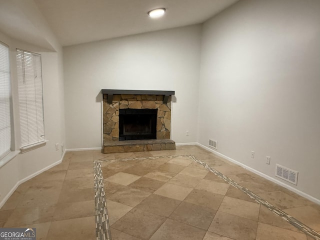 unfurnished living room with vaulted ceiling and a stone fireplace