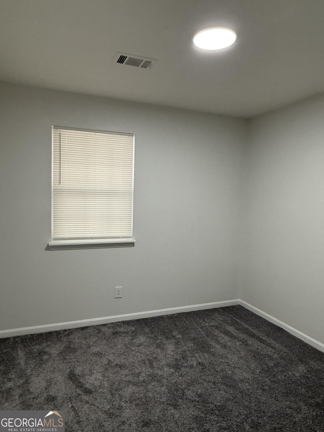 spare room featuring dark carpet