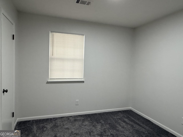 unfurnished room featuring dark colored carpet