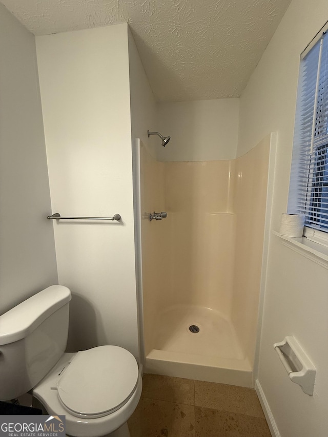 bathroom featuring toilet, a textured ceiling, and walk in shower