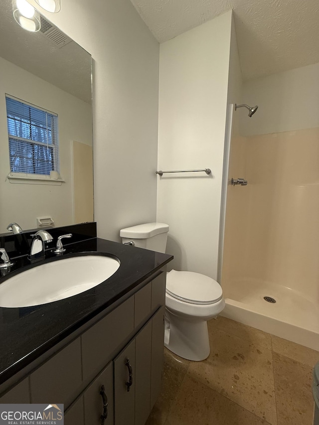 bathroom featuring walk in shower, vanity, toilet, and a textured ceiling