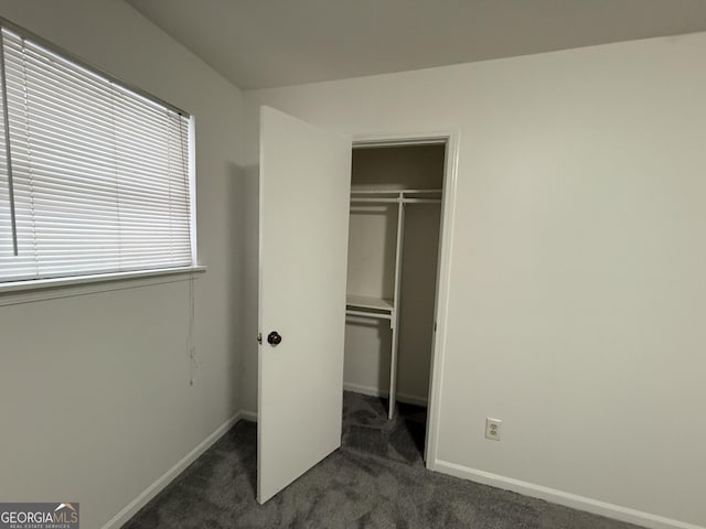 unfurnished bedroom featuring dark carpet and a closet