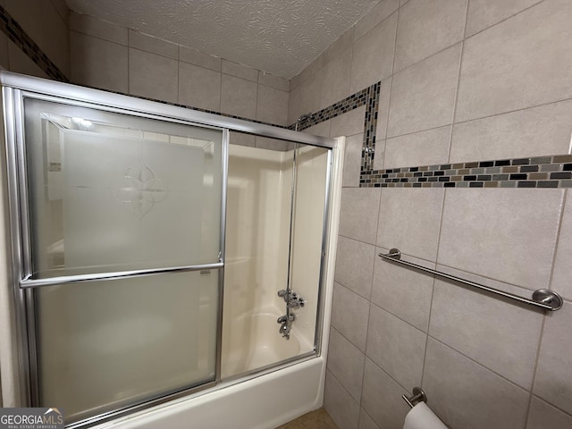 bathroom with enclosed tub / shower combo and a textured ceiling