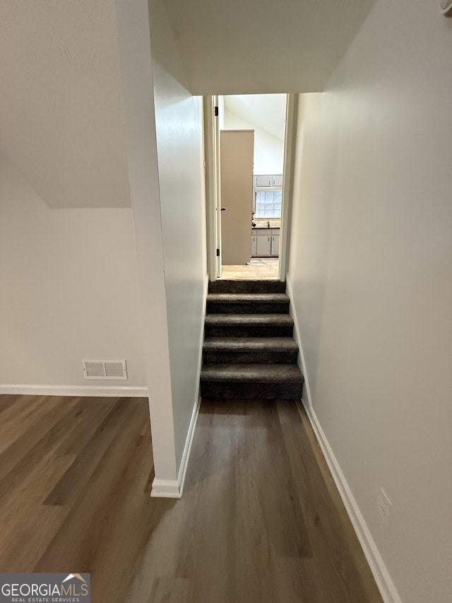 stairs featuring vaulted ceiling and hardwood / wood-style floors