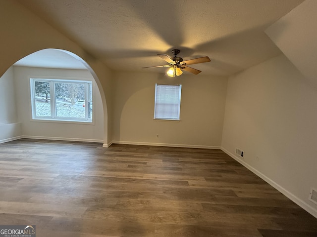 additional living space with ceiling fan, dark wood-type flooring, and a textured ceiling