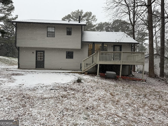 snow covered rear of property with a deck