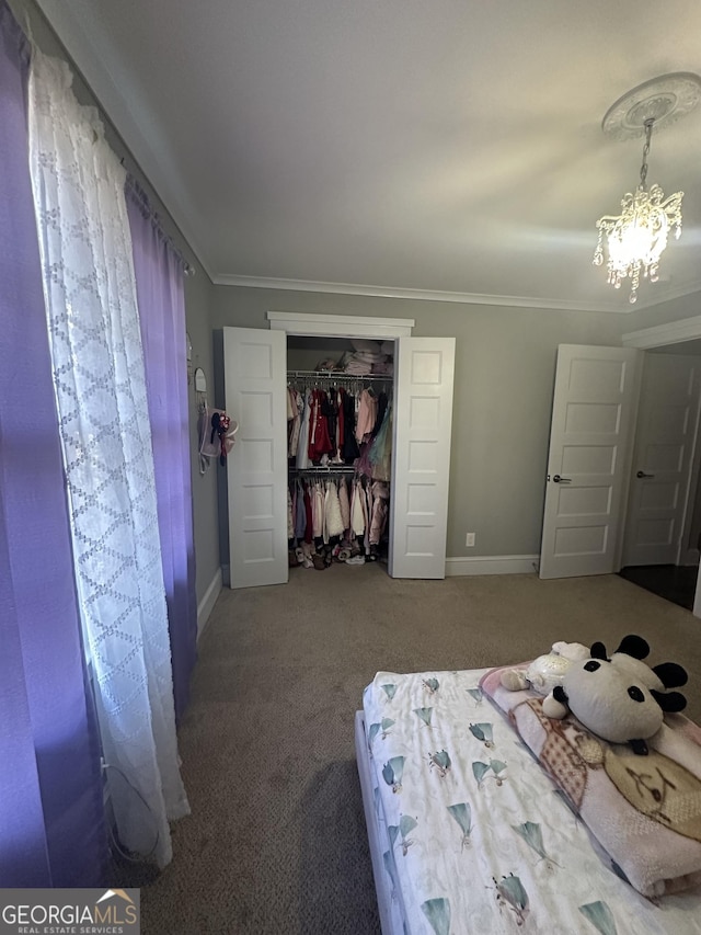 carpeted bedroom with a closet, ornamental molding, and a notable chandelier