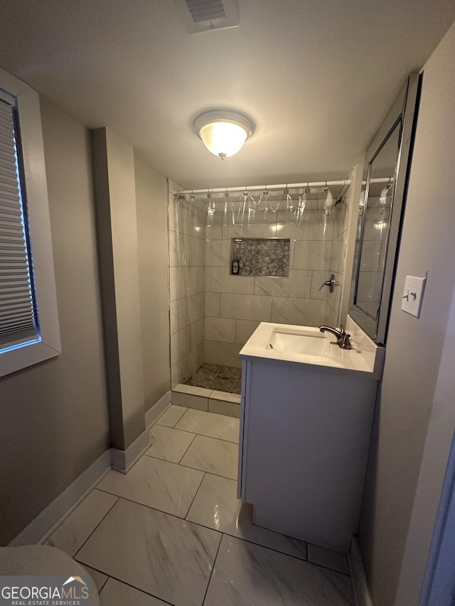 bathroom featuring a tile shower and vanity