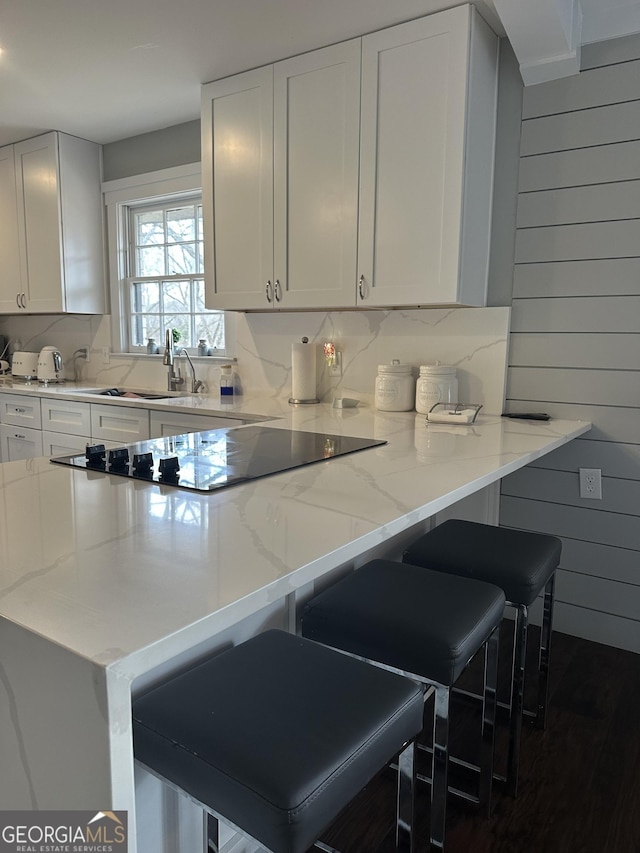 kitchen featuring sink, kitchen peninsula, a kitchen bar, and wooden walls