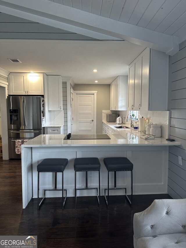 kitchen with white cabinetry, stainless steel fridge, and kitchen peninsula