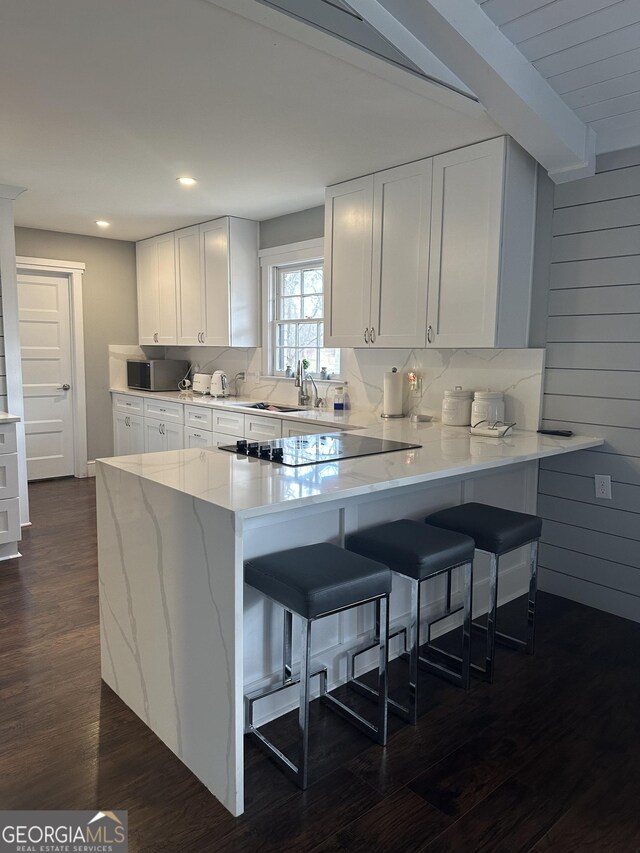 kitchen featuring white cabinets, kitchen peninsula, dark wood-type flooring, and sink