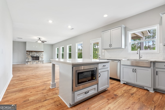 kitchen with a center island, a fireplace, gray cabinetry, sink, and stainless steel appliances