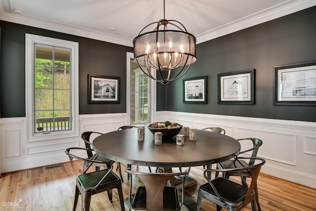 dining space with light hardwood / wood-style flooring, an inviting chandelier, and crown molding