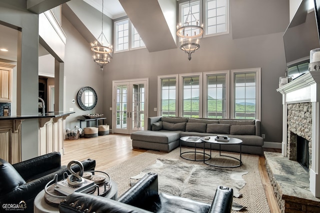 living room featuring a fireplace, an inviting chandelier, a wealth of natural light, and french doors