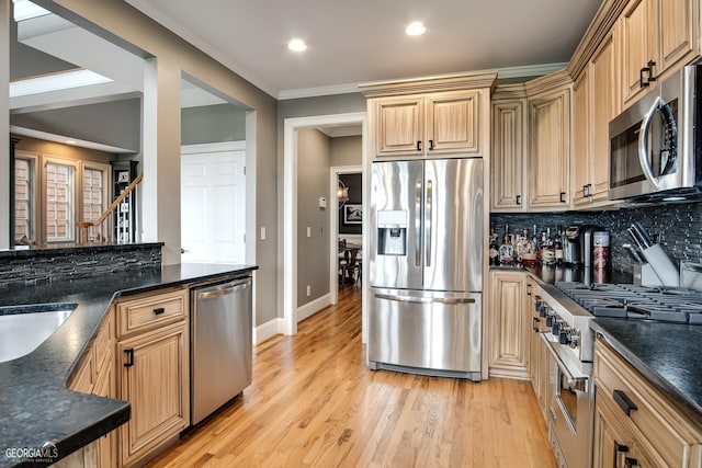 kitchen with stainless steel appliances, dark stone counters, decorative backsplash, light hardwood / wood-style floors, and crown molding