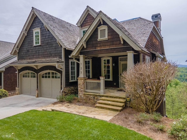 craftsman house featuring a garage, a porch, and a front lawn