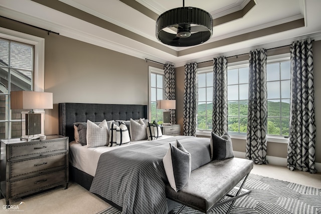 bedroom with light colored carpet, crown molding, and a tray ceiling