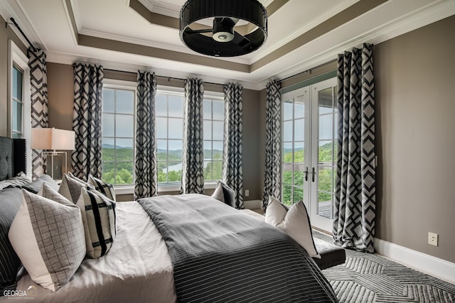 bedroom with ornamental molding, a tray ceiling, and french doors