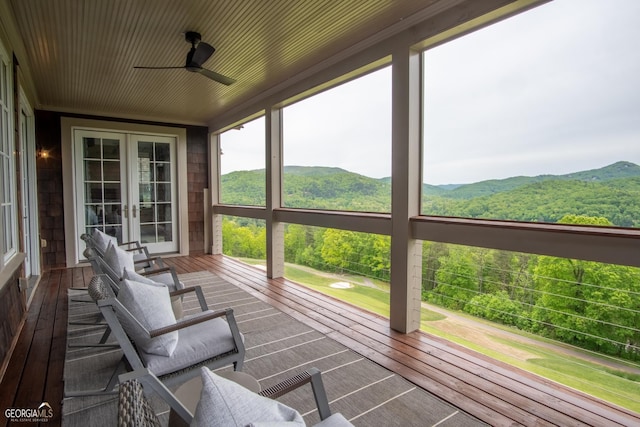 sunroom with a mountain view, ceiling fan, and french doors