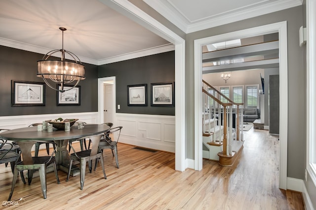 dining room with light hardwood / wood-style floors, ornamental molding, and an inviting chandelier