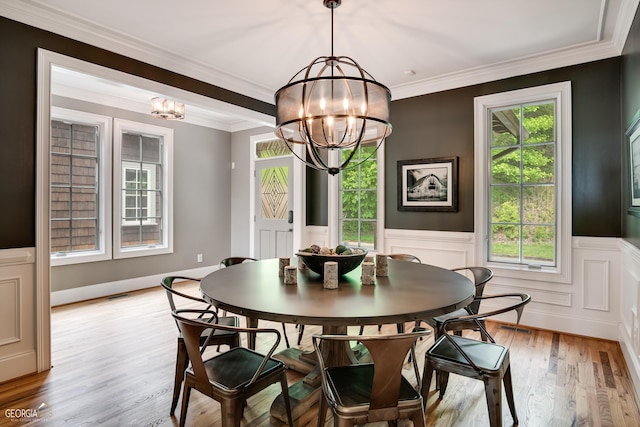 dining area featuring a chandelier, light wood-type flooring, a wealth of natural light, and crown molding