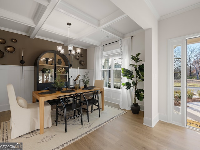 dining space featuring light wood-type flooring, ornamental molding, coffered ceiling, a notable chandelier, and beam ceiling