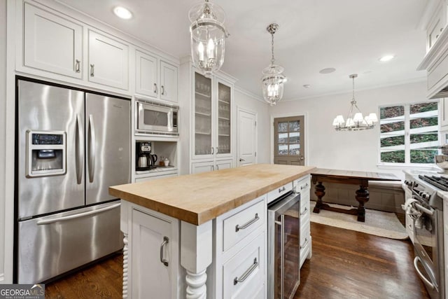 kitchen with appliances with stainless steel finishes, wooden counters, wine cooler, white cabinets, and a center island