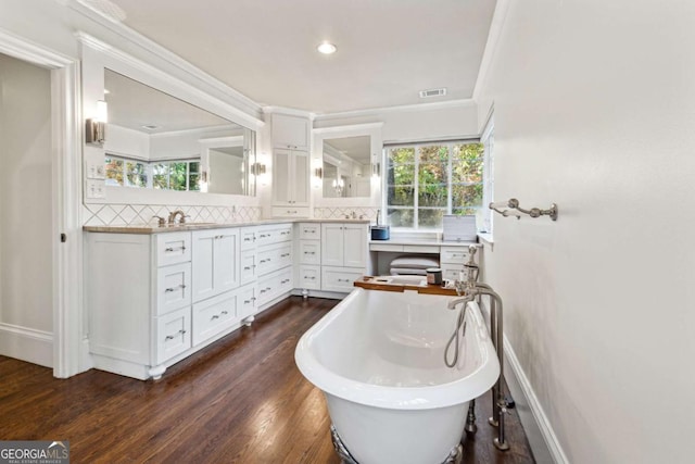 bathroom featuring a bathtub, decorative backsplash, hardwood / wood-style flooring, vanity, and ornamental molding