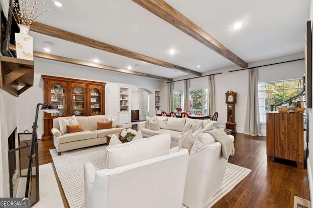 living room featuring dark hardwood / wood-style flooring, a large fireplace, and beamed ceiling