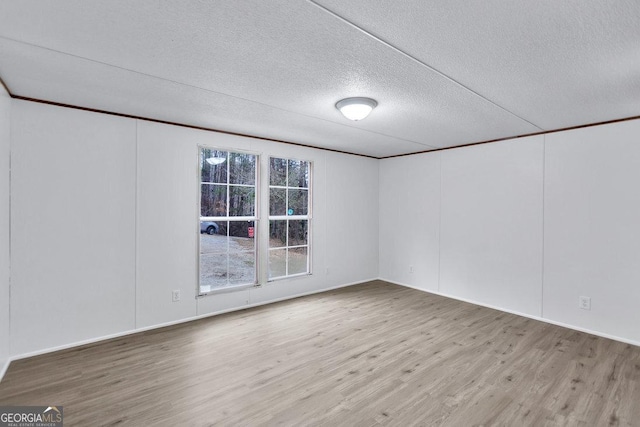 spare room with light wood-type flooring and a textured ceiling