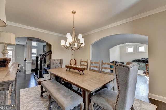 dining space with a wealth of natural light, crown molding, dark hardwood / wood-style flooring, and ornate columns