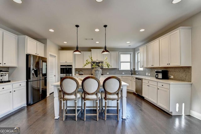 kitchen with white cabinetry, hanging light fixtures, sink, a kitchen island, and stainless steel appliances